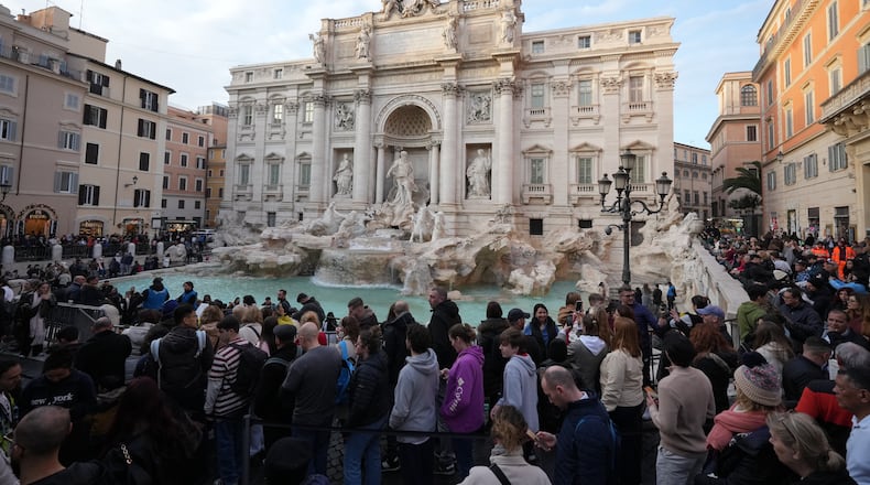 Visitors admire Rome's Trevi Fountain, Friday, Dec. 19, 2025, as the city municipality announced that, starting on Feb. 1, it will impose a 2 euro fee for tourists to visit the recessed fountain edge. (AP Photo/Andrew Medichini)