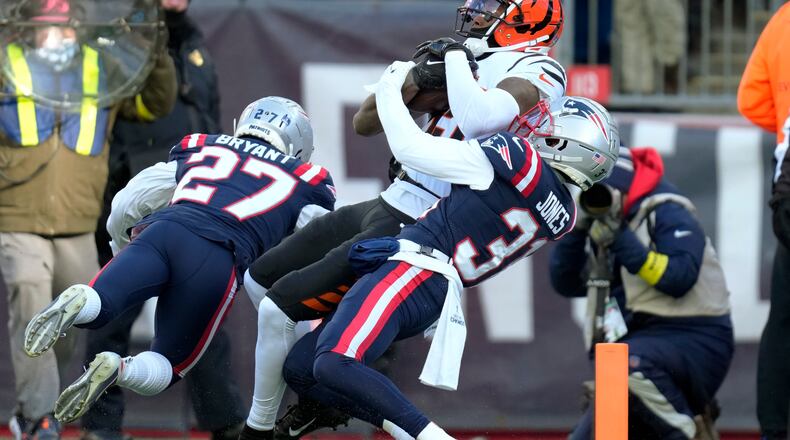 Cincinnati Bengals wide receiver Tee Higgins, center, enters the end zone for a touchdown as New England Patriots cornerback Myles Bryant (27) and cornerback Jonathan Jones (31) try to defend during the first half of an NFL football game, Saturday, Dec. 24, 2022, in Foxborough, Mass. (AP Photo/Charles Krupa)