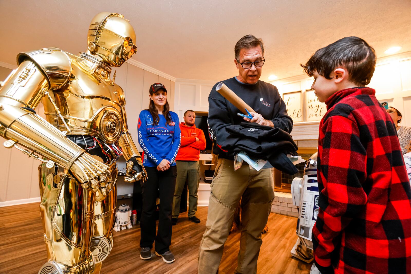 Team Fastrax members John Hart and Nicole Condrey present a Dreams of Fastrax certificate for a family plane ride and indoor wind tunnel session to Porter Sowards, a 10-year-old who is battling brain cancer, as he was surprised with a visit from Star Wars characters, C3PO, portrayed by Tim O'Sullivan, R2D2 and Chewbacca, portrayed by Joey Arielle, at his home Friday, Nov. 12, 2021 in Middletown. NICK GRAHAM / STAFF