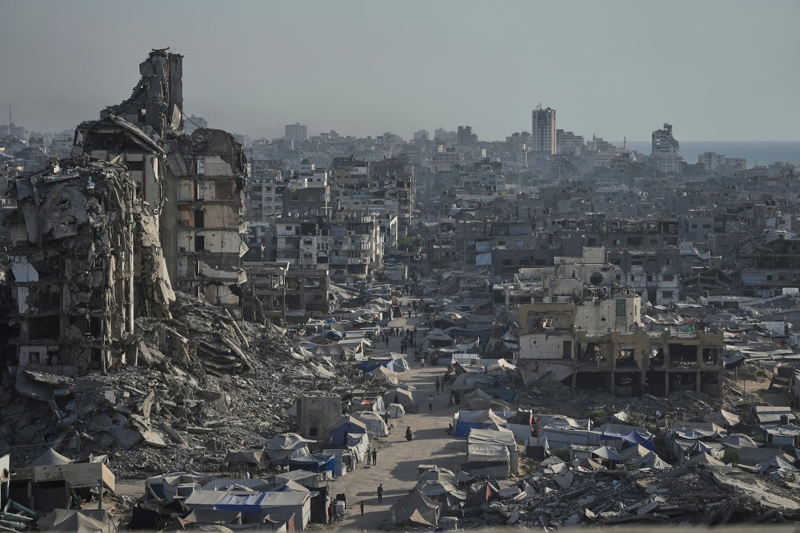 Tents sheltering displaced Palestinians are seen amid war-damaged infrastructure in Gaza City, Thursday, July 17, 2025. (AP Photo/Jehad Alshrafi)