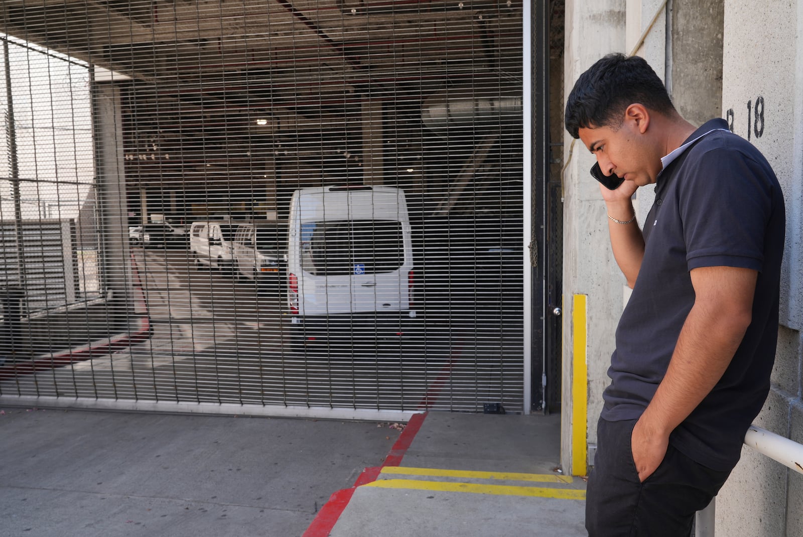 Alejandro Barranco talks on his cell phone outside the Metropolitan Detention Center, where is father Narciso is detained, on Monday, June 23, 2025, in Los Angeles. (AP Photo/Damian Dovarganes)