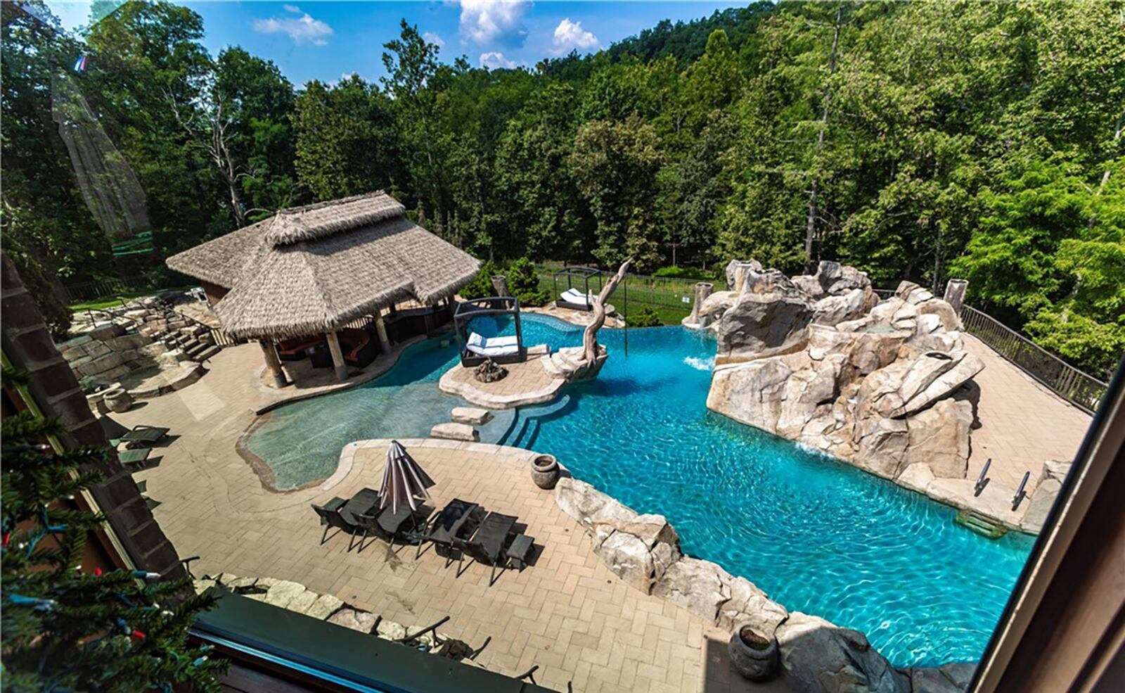 The resort style pool area has an infinity edge, rock formations and slides, fountains and a glass wall hot tub. CONTRIBUTED