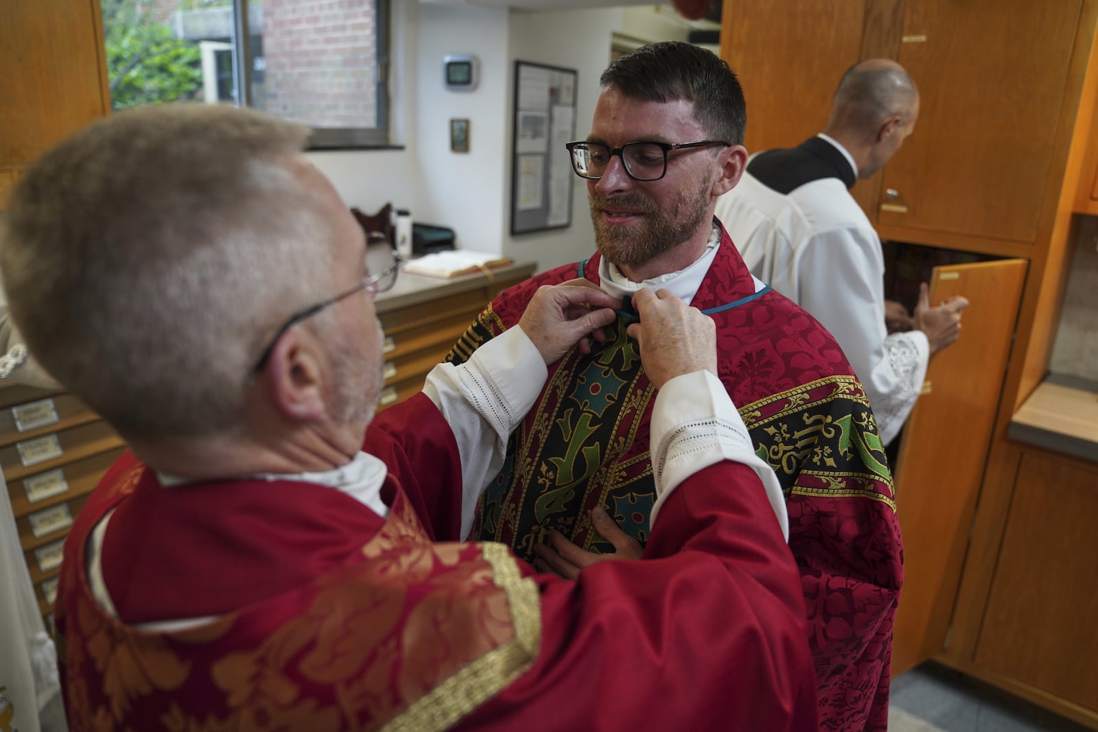 The Rev. Donald J. Planty, Jr., left, assists the Rev. Tim Banach with a microphone before Banach's first Mass at St. Charles Borromeo Catholic Church in Arlington, Va., on Sunday, June 8, 2025. (AP Photo/Jessie Wardarski)
