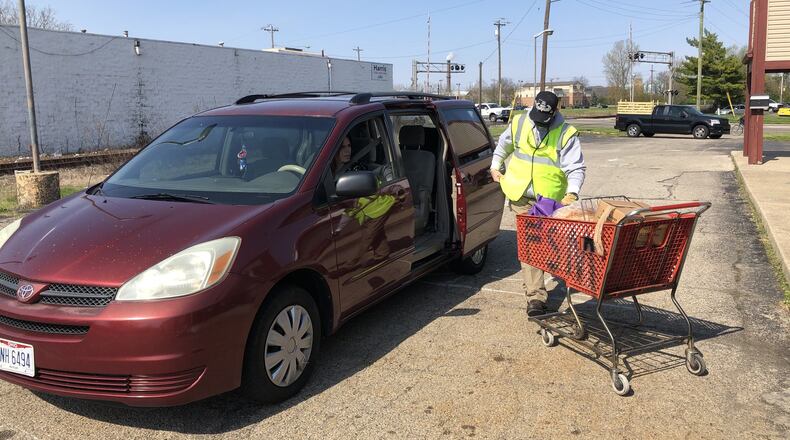 Family Service of Middletown has changed the way it distributes food to its clients. People now drive through, stay in their vehicles and are given food by staff or volunteers. RICK McCRABB/STAFF