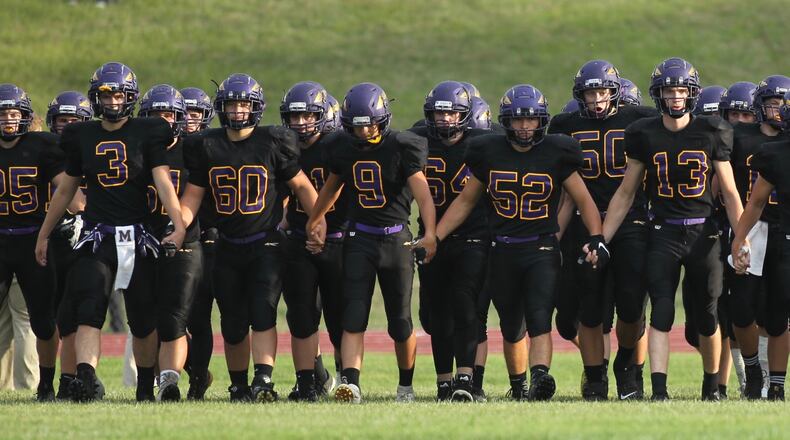 Mechanicsburg players hold hands as they take the field before a game against Kenton Ridge on Friday, Aug. 30, 2019, at Mechanicsburg. David Jablonski/Staff