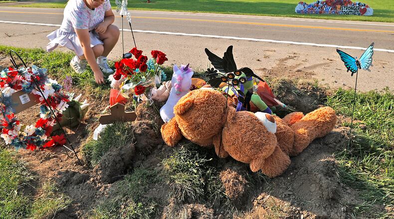 Madison Donnelly, a Northwestern Schools alumnus, places flowers Wednesday, August 23, 2023 at a memorial along Troy Road at the site of Tuesday's fatal bus crash. BILL LACKEY/STAFF