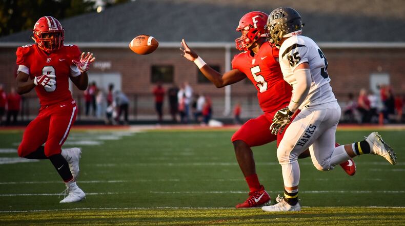 Fairfield quarterback Jeff Tyus (5) flips the ball to Jutahn McClain (9) on the option while being defended by Lakota East’s Christopher Whitehead last Friday night at Fairfield Stadium. The host Indians won 48-14.. NICK GRAHAM/STAFF