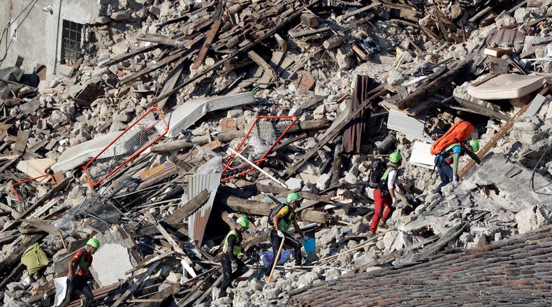 Rescuers make their way through destroyed houses following an earthquake in Pescara Del Tronto, central Italy, Thursday, Aug. 25, 2016. The magnitude 6 quake struck Wednesday at 3:36 a.m. (0136 GMT) and was felt across a broad swath of central Italy, including Rome where residents of the capital felt a long swaying followed by aftershocks. (AP Photo/Gregorio Borgia)