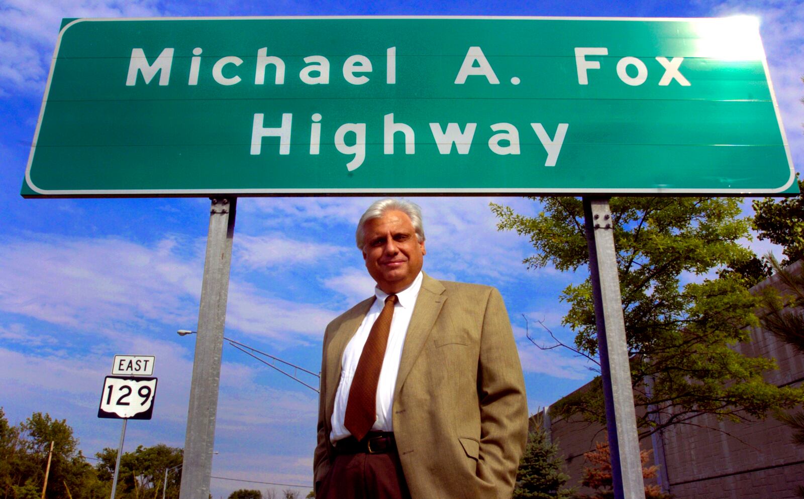 Mike Fox poses for a photo under a sign marking the Michael A. Fox Highway, Wednesday June 9, 2004, in Hamilton, Ohio. Officials in Butler County, where the Hispanic population has grown by 500 percent since 1990, said they hope to enact a state trespassing law for illegal immigrants. Combs, County Commissioner Mike Fox and Sheriff Rick Jones contend federal resources are stretched too thin to adequately police the region's ballooning immigrant population. (AP Photo/The Cincinnati Enquirer, Glenn Hartong)