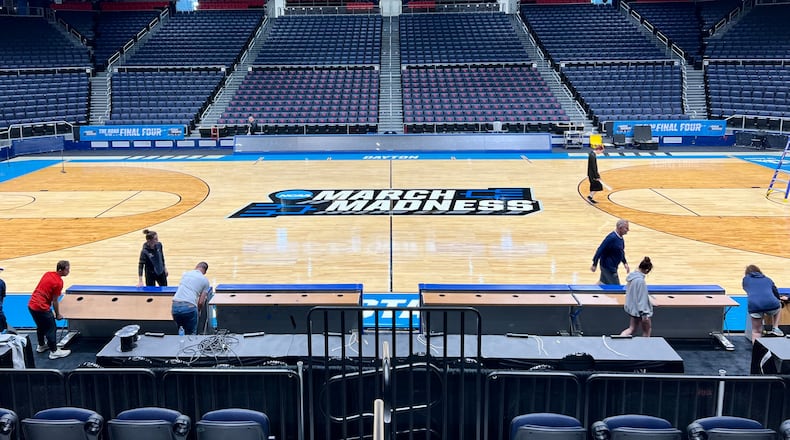 Workers on Sunday put the finishing touches on the basketball court installation for the First Four of the NCAA Division I Men’s Basketball Championship at UD Arena. AIMEE HANCOCK/STAFF