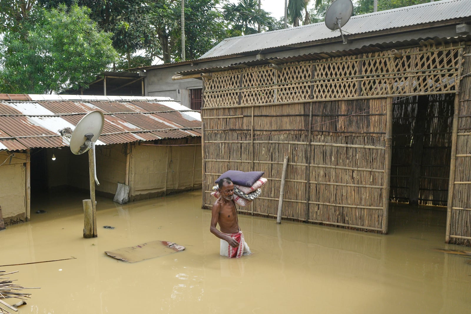 FILE - A villager wades through floodwaters to reach safer places after days of torrential monsoon rains in Kampur in India's northeastern state of Assam, June 2, 2025. (AP Photo, File)
