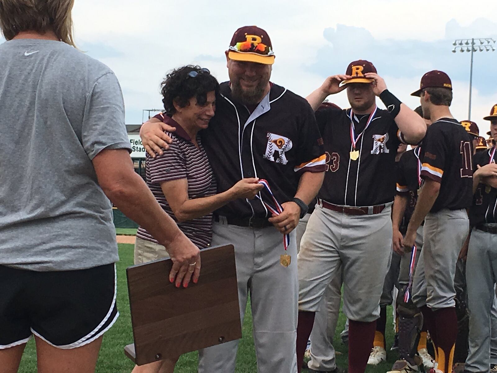 Ross coach Jason Rettinger gets a hug from athletic director Micky Geier during the awards ceremony at Mason on Monday after the Rams defeated Tippecanoe 6-3 to repeat as Division II district champions. RICK CASSANO/STAFF