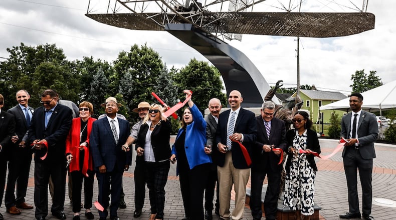 City of Dayton officials pose for pictures in front of the Wright Flyer III sculpture following the ribbon cutting ceremony at the intersection of Edwin C. Moses and West Third Street Wednesday 14, 2023. The sculpture was moved from Monument Avenue after a developer bought the land. JIM NOELKER/STAFF