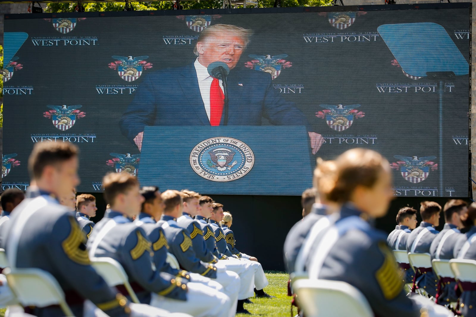 FILE - President Donald Trump is shown on a video screen as he speaks to U.S. Military Academy graduating cadets during commencement ceremonies in West Point, N.Y., June 13, 2020. (AP Photo/John Minchillo, Pool, File)