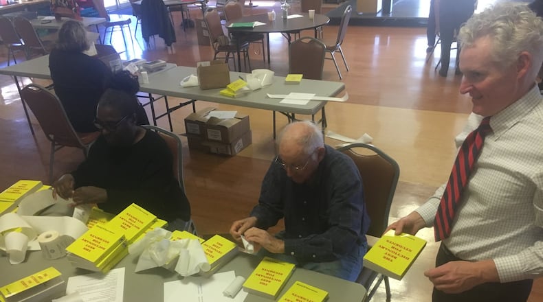 Middletown Rotary Club members, from left, Debra Patterson, Fred Sauer and Joe Mulligan, prepare dictionaries that will be distributed to every third-grader in the service area. RICK McCRABB/STAFF