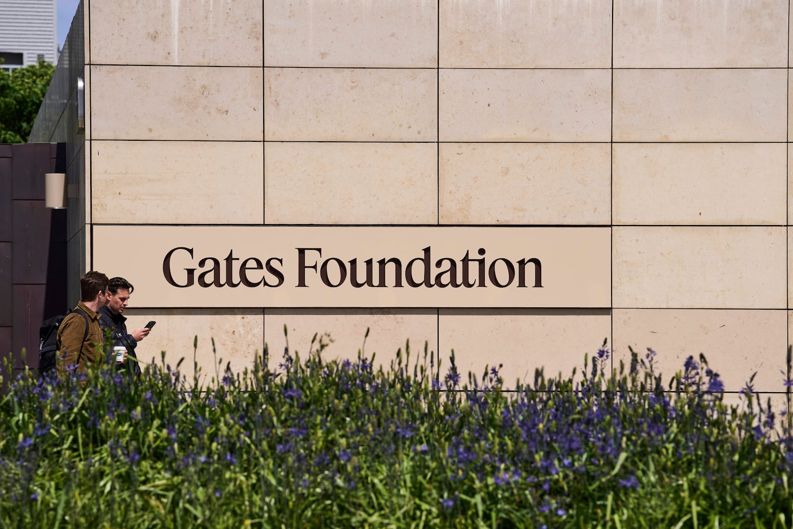 People walk by a Gates Foundation sign at the foundation's campus Wednesday, April 30, 2025, in Seattle. (AP Photo/Lindsey Wasson)