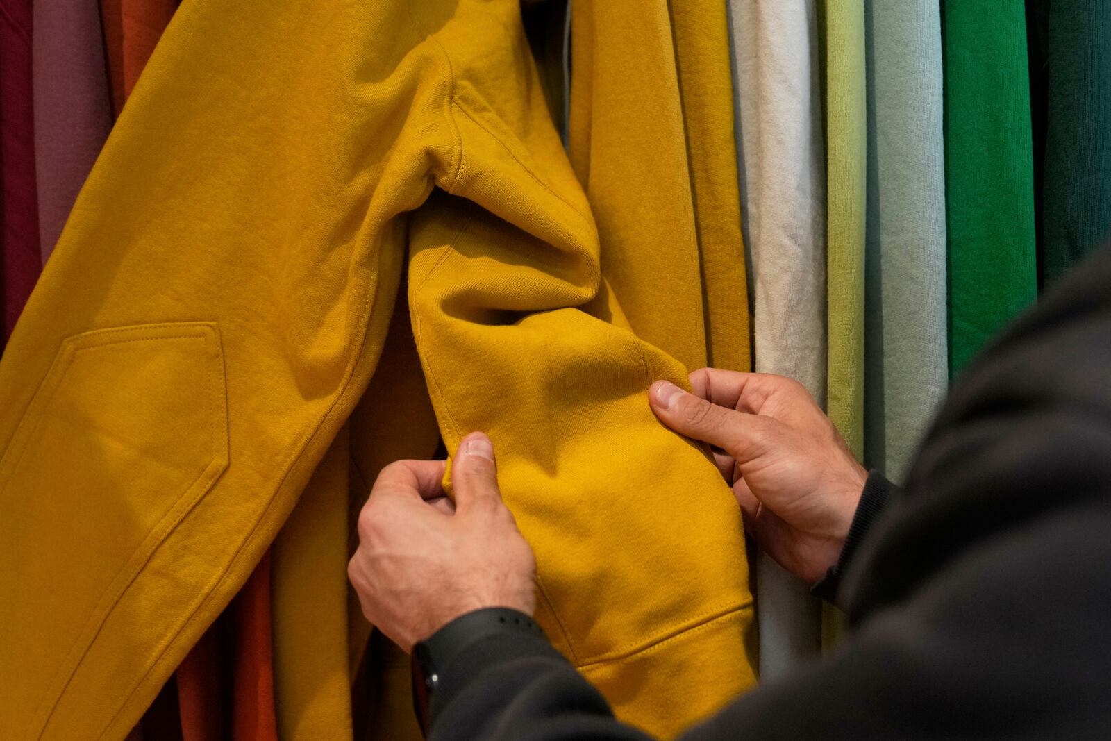 Javid Moghaddasnia, Director of Customer Engagement, holds the sleeve to an American Giant hoodie while being interviewed at the company's showroom in San Francisco, Thursday, April 17, 2025. (AP Photo/Jeff Chiu)