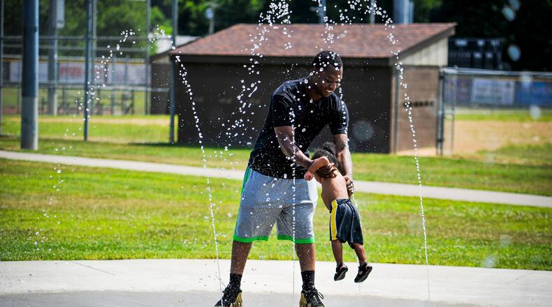 Brian Cleckley swings his son, Braxton Cleckley, 1, through the water at the splash pad outside the Booker T. Washington Community Center on S. Front Street Thursday, July 11 in Hamilton. Another heat wave is expected to hit Butler County this weekend with the heat index reaching above 100 degrees. NICK GRAHAM/STAFF