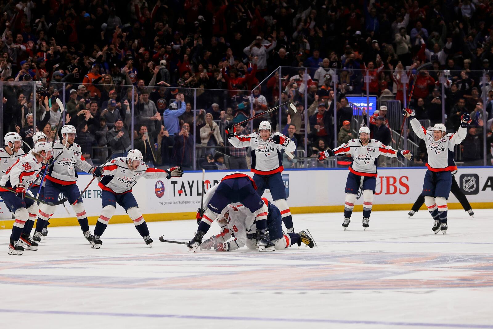 Washington Capitals left wing Alex Ovechkin (8), lower center, is celebrates with is teammates after scoring against New York Islanders during the second period of an NHL hockey game in Elmont, N.Y., Sunday, April 6, 2025. (AP Photo/Adam Hunger)