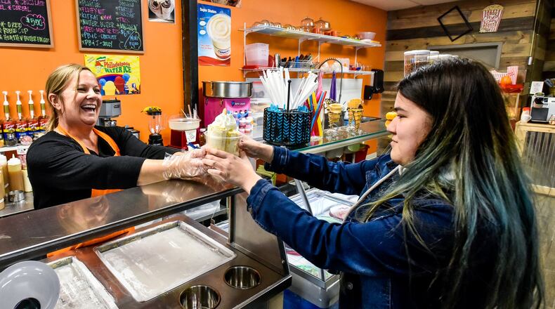Missy Wagner, left, hands over a freshly made rolled ice cream to Emrie Adelhardt, 17, at Candy Stash Sweets & Treats Wednesday, Nov. 20, 2019 at 7125 Liberty Centre Drive in Liberty Township. Wagner opened Candy Stash in the space previously occupied by another candy shop. The location offers a variety of packaged and bulk candy, rolled ice cream, hand dipped ice cream, premium Philly Ice, specialty drinks and more. NICK GRAHAM/STAFF