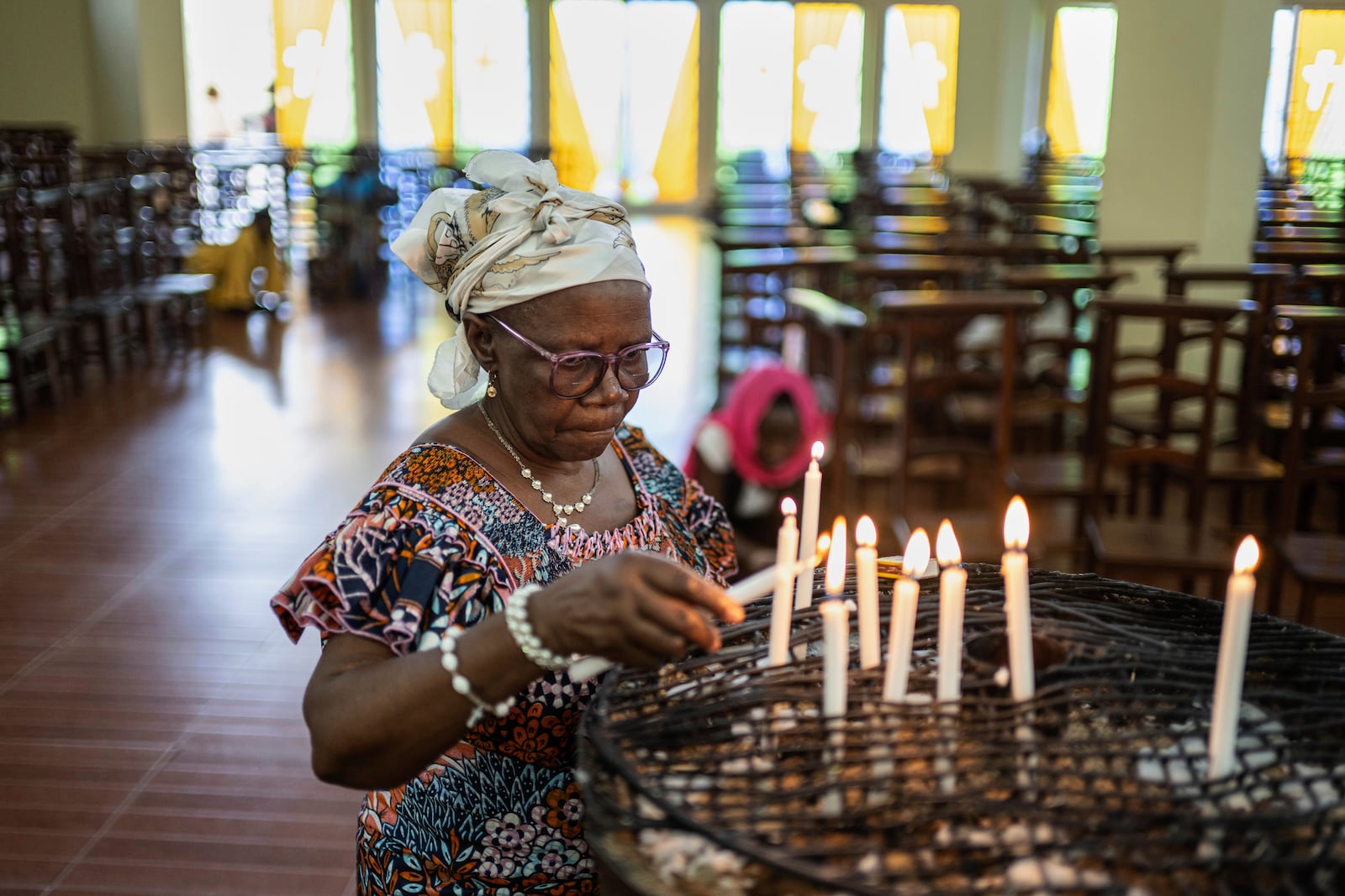 A woman lights candles in memory of Pope Francis during the morning mass at the Sanctuaire d'adoration cathedral, following the announcement of his death in Goma, Democratic Republic of Congo, Monday, April 21, 2025. (AP Photo/Moses Sawasawa)