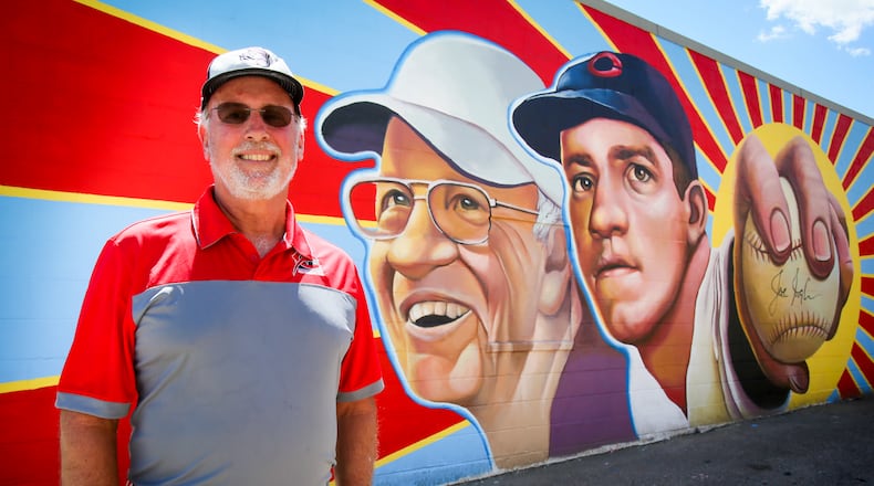 Kim Nuxhall stands with a the Hamilton mural featuring his father, Cincinnati Reds legend, Joe Nuxhall, painted on the side of Clark’s Sporting Goods on Hamilton’s west side. GREG LYNCH / STAFF