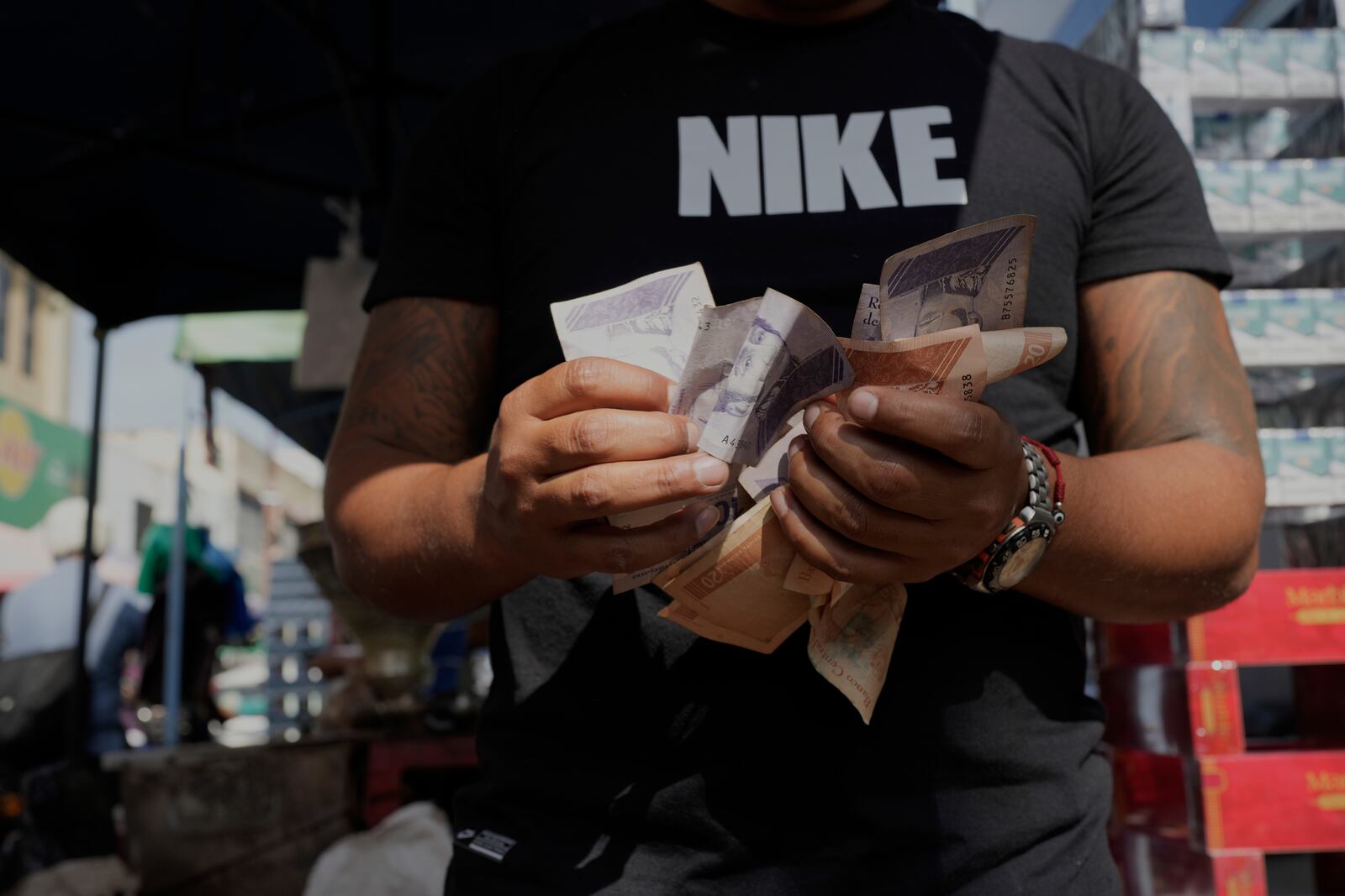 A man counts Venezuelan Bolivars at a street market in Caracas, Venezuela, Friday, April 11, 2025. (AP Photo/Ariana Cubillos)