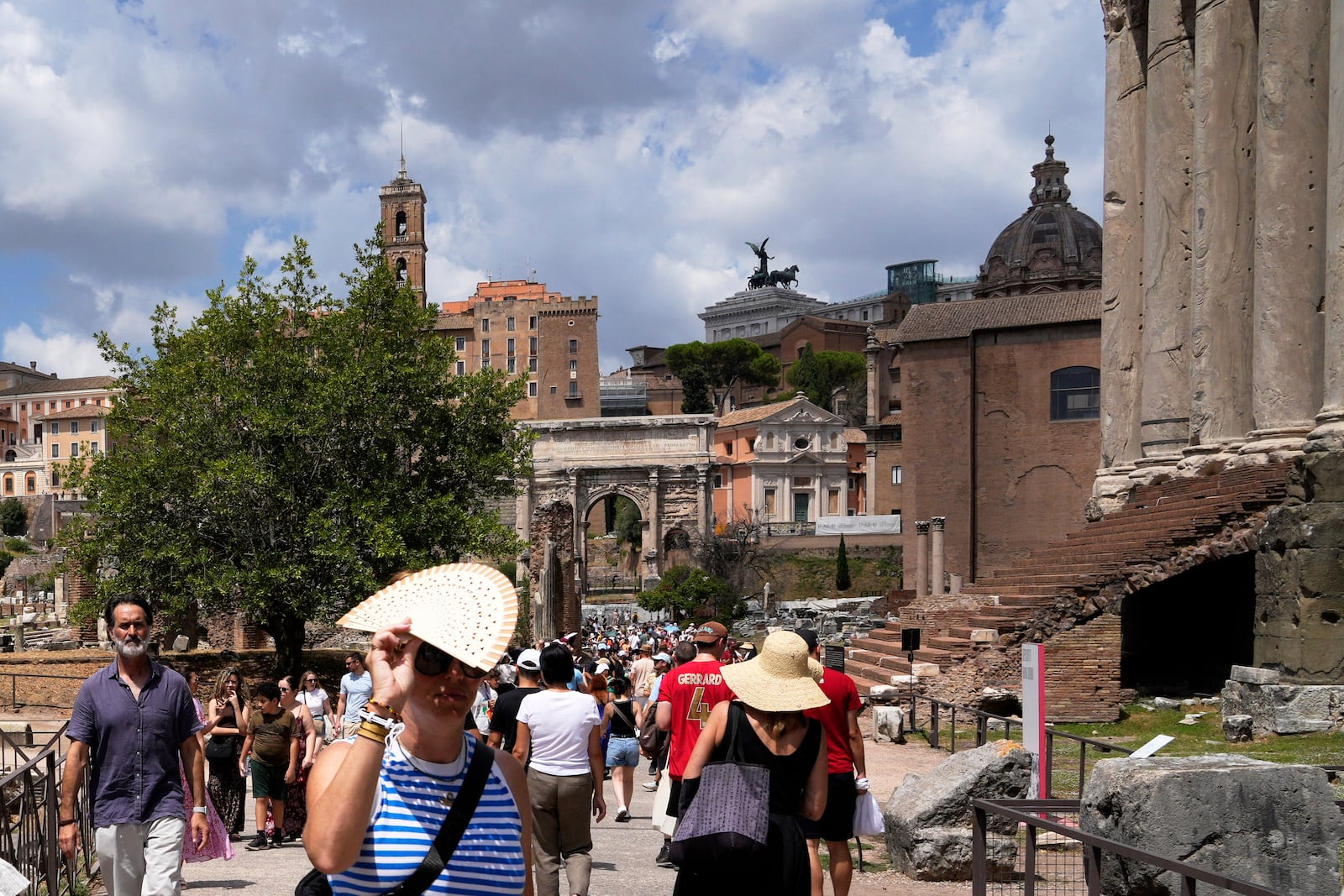 Tourists use use fans and sun hats as they visit the Forum in Rome on Tuesday, July 22, 2025. (AP Photo/Gregorio Borgia)