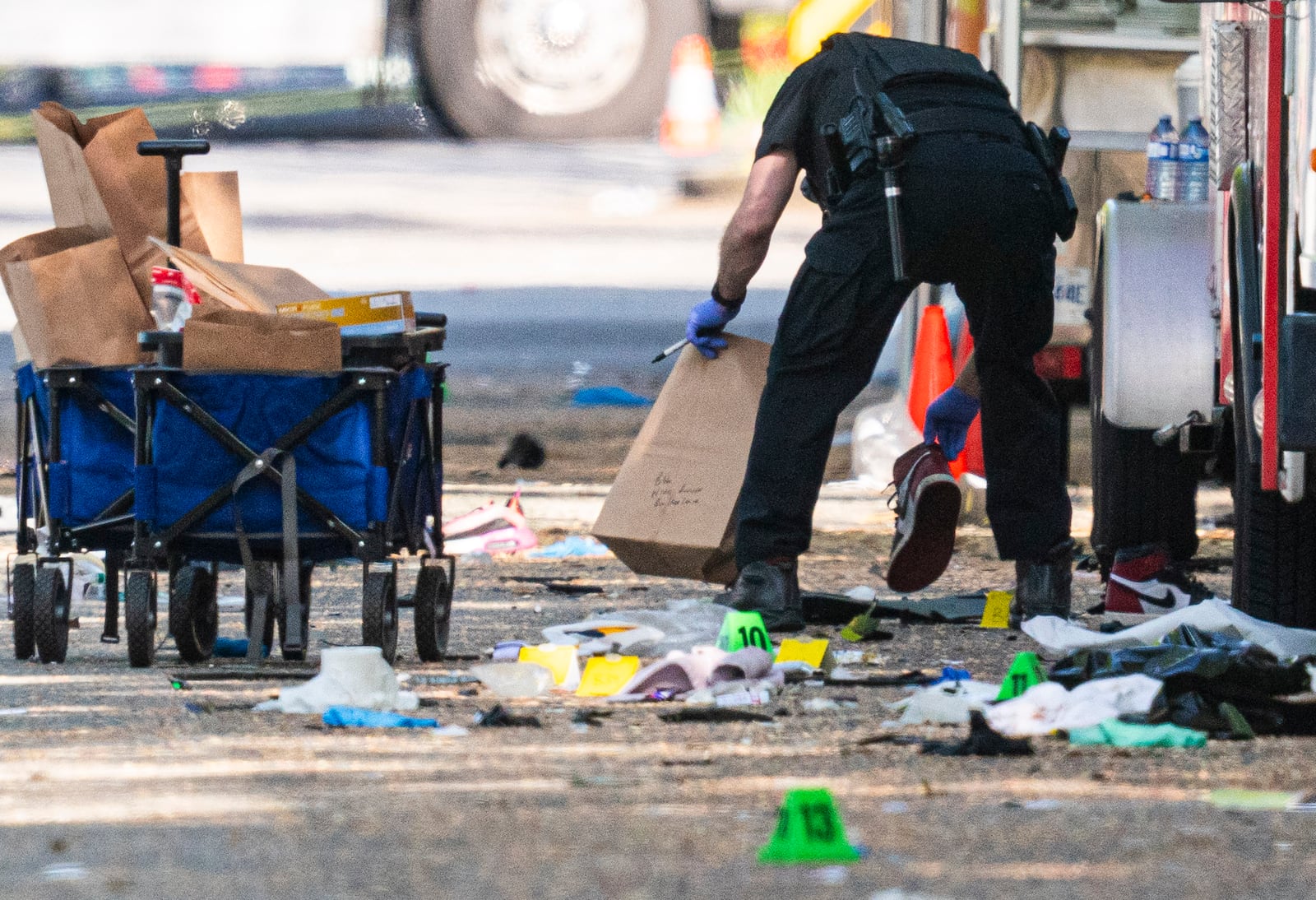 A member of the Vancouver Police forensics team picks up a shoe while investigating the scene where a vehicle drove into a crowd Saturday night at a street festival, in Vancouver, British Columbia, Sunday, April 27, 2025. (Rich Lam/The Canadian Press via AP)