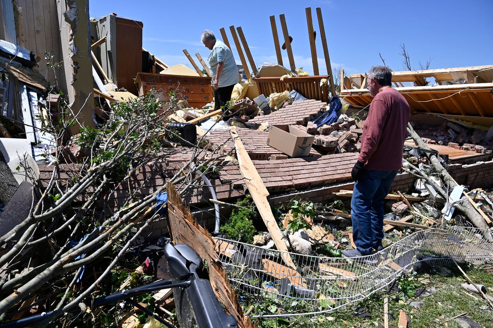 Doris Hensley, center, and Don Allen look over the remains of her home following severe weather in London, Ky., Saturday, May 17, 2025. (AP Photo/Timothy D. Easley)
