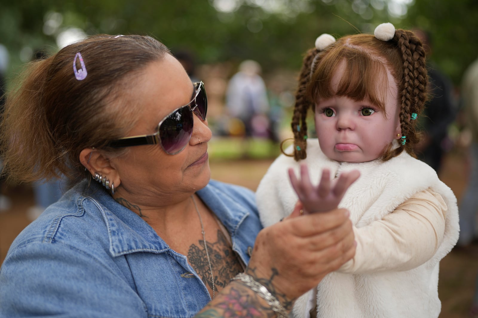 Nice Maria Santos holds her doll during a group gathering to bond and show off their hyper-realistic reborn baby dolls, in a park in Sao Paulo, Saturday, May 24, 2025. (AP Photo/Andre Penner)