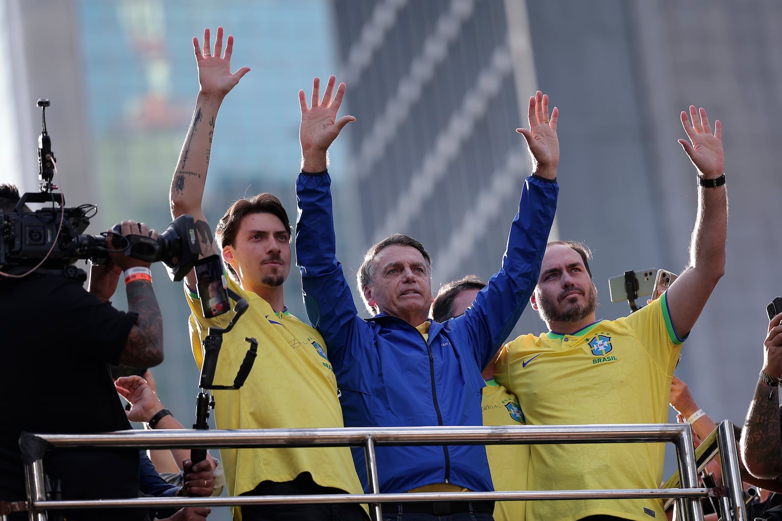 Former President Jair Bolsonaro, center, gestures to the crowd with his sons Jair Renan Bolsonaro, left, and Carlos Bolsonaro, during a protest against his Supreme Court trial, in which he is accused of involvement in a 2022 coup attempt, in Sao Paulo, Sunday, June, 29, 2025. (AP Photo/Ettore Chiereguini)