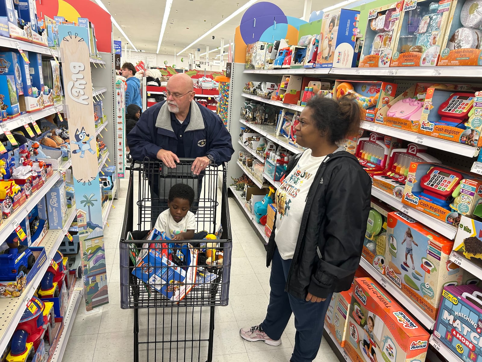 Steve Bohannon, president of the Fraternal Order of Police Auxiliary, helps Razer, 2, shop for toys as his mother, Rosie Redmond, looks on. RICK McCRABB/CONTRIBUTOR