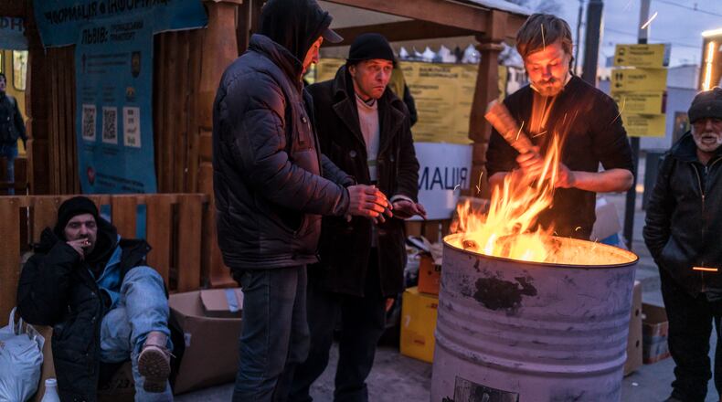 People who fled the fighting near their homes gather around a fire outside the central train station in Lviv, Ukraine, on Wednesday, March 9, 2022. With Ukrainian resistance holding firm and Western penalties seemingly toughening by the hour, the cost to Russia of its troubled, nearly two-week invasion mounted on Wednesday as its Central Bank limited withdrawals of foreign currency to protect the crashing ruble and the Kremlin’s spokesman accused the United States of waging an “economic war.” (Brendan Hoffman/The New York Times)