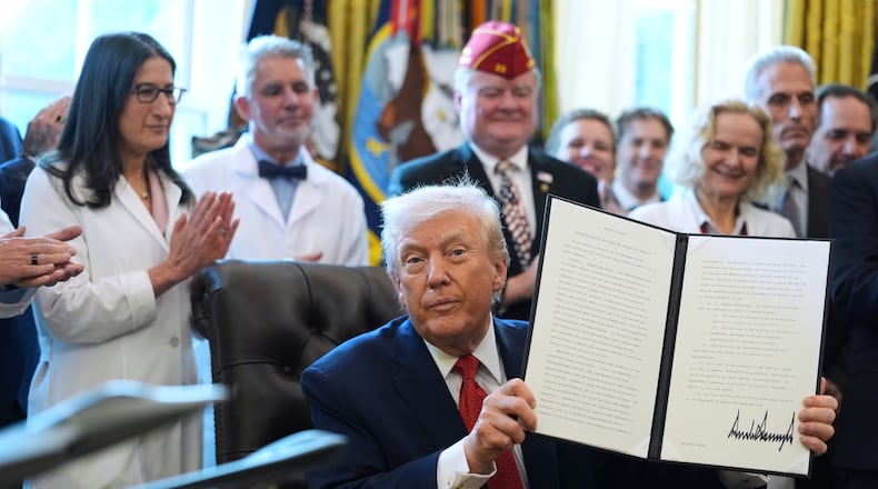 President Donald Trump displays an executive order reclassifying marijuana as a less dangerous drug in the Oval Office of the White House, Thursday, Dec. 18, 2025, in Washington. (AP Photo/Evan Vucci)