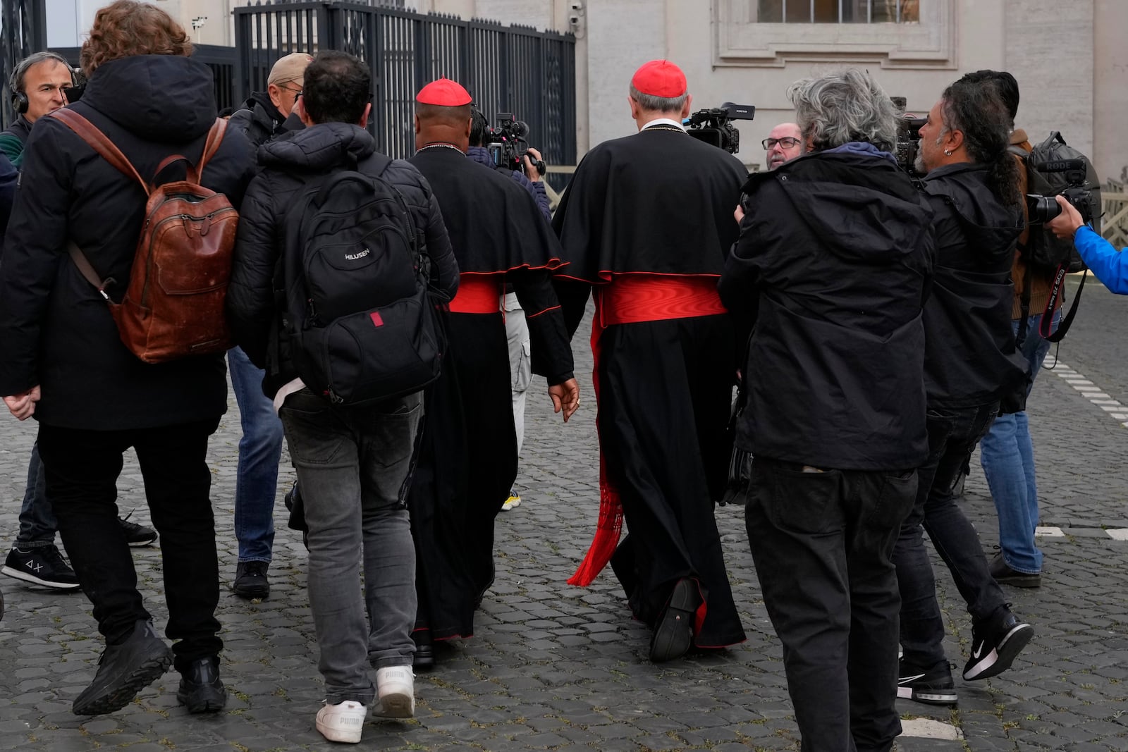 Cardinal Pierbattista Pizzaballa, center right, and Cardinal Fridolin Ambongo Besungu are surrounded by reporters as they arrive for a college of cardinals' meeting, at the Vatican, Monday, April 28, 2025. (AP Photo/Gregorio Borgia)