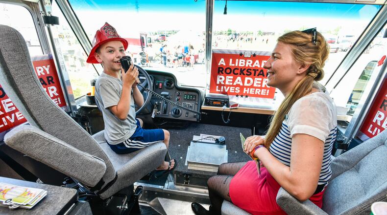 MidPointe Library's Jenn Effinger lets Jack Whitehouse, 8, talk on the speaker inside MidPointe's Library on Wheels during West Chester Township's Touch A Truck event Friday, June 15 at The Square @ Union Centre. Fire trucks, police vehicles, helicopters, lift trucks, snow plows and more were on display for kids to climb in and honk horns during the free event. NICK GRAHAM/STAFF