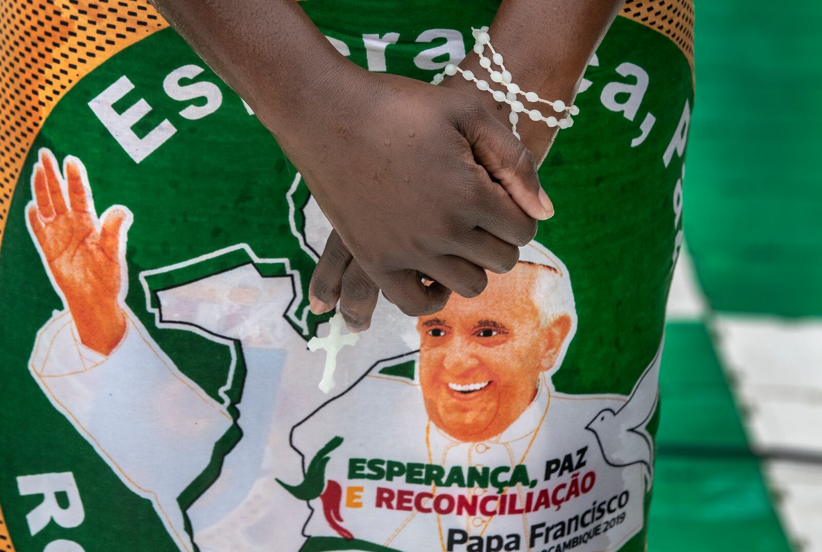 FILE - A woman holds a rosary as she stands in the rain during a Mass celebrated by Pope Francis at Zimpeto stadium on the outskirts of Maputo, Mozambique, Sept. 6, 2019. (AP Photo/Ben Curtis, File)