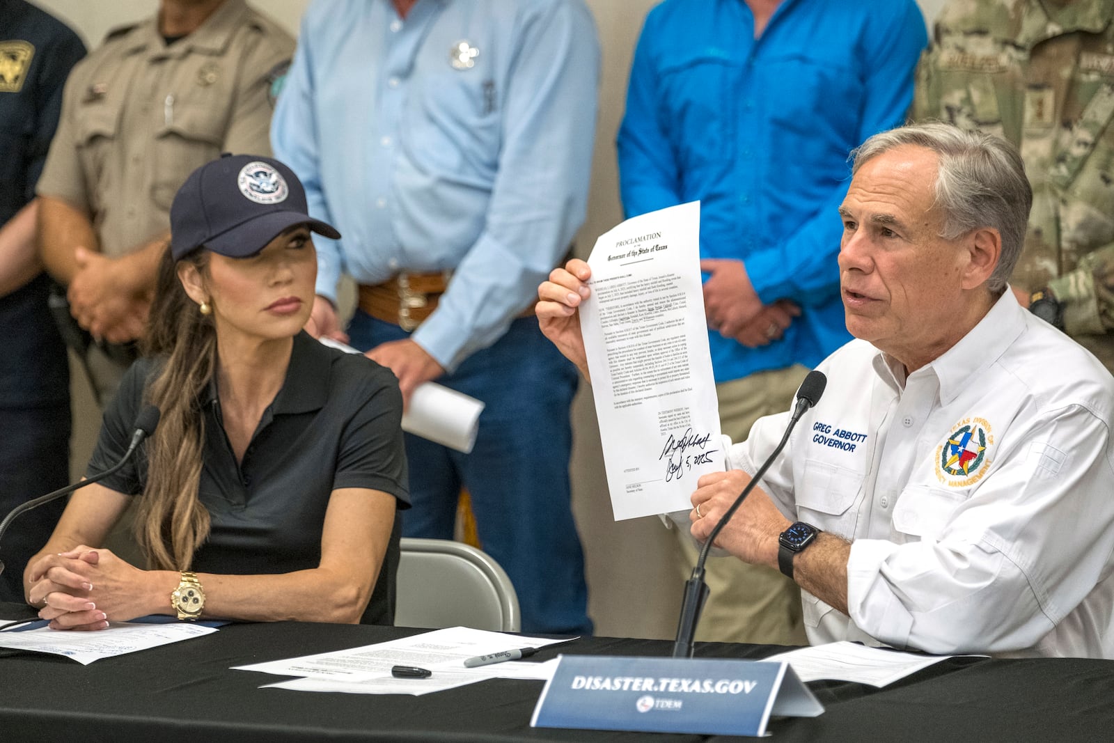 Texas Gov. Greg Abbott signs and holds up an disaster declaration proclamation as Homeland Security Secretary Kristi Noem, left, looks on during a press conference about recent flooding along the Guadalupe River, Saturday, July 5, 2025, in Kerrville, Texas. (AP Photo/Rodolfo Gonzalez)