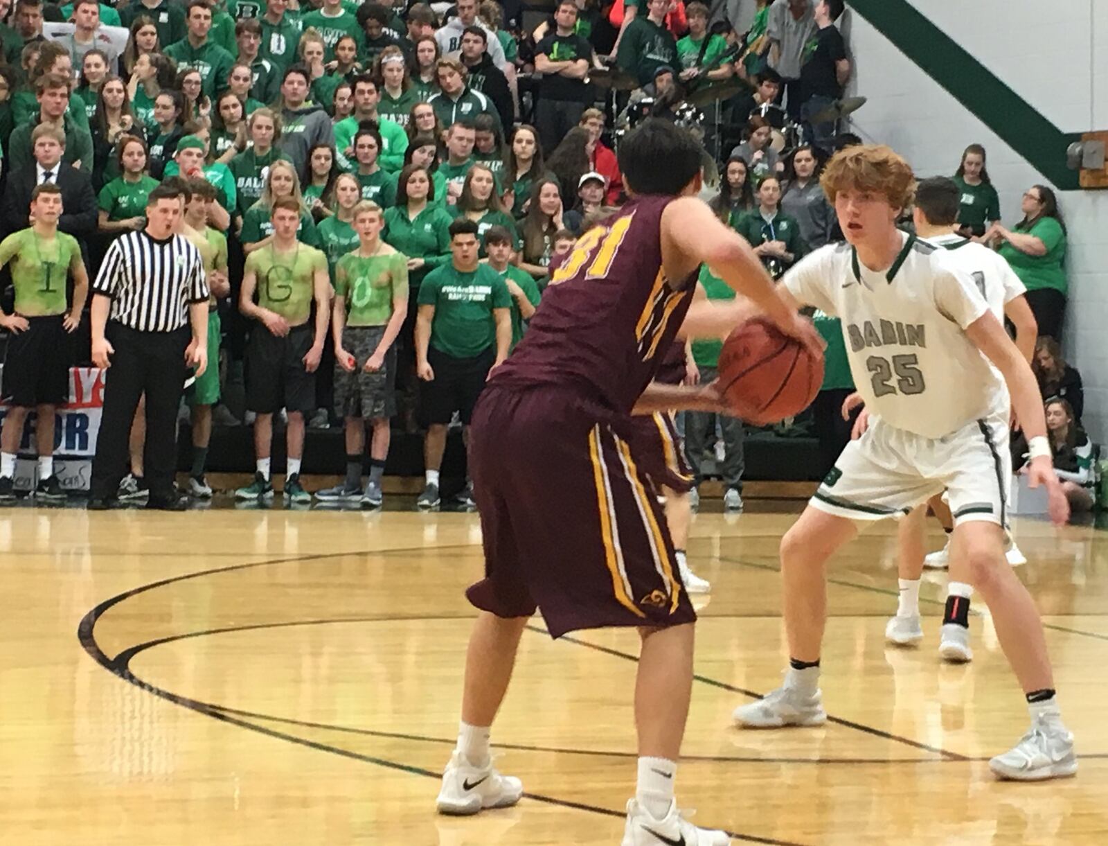 Badin’s Zach Switzer (25) guards Sean Lange (31) of Ross as the Badin student section watches the action during Saturday night’s game at Mulcahey Gym in Hamilton. RICK CASSANO/STAFF