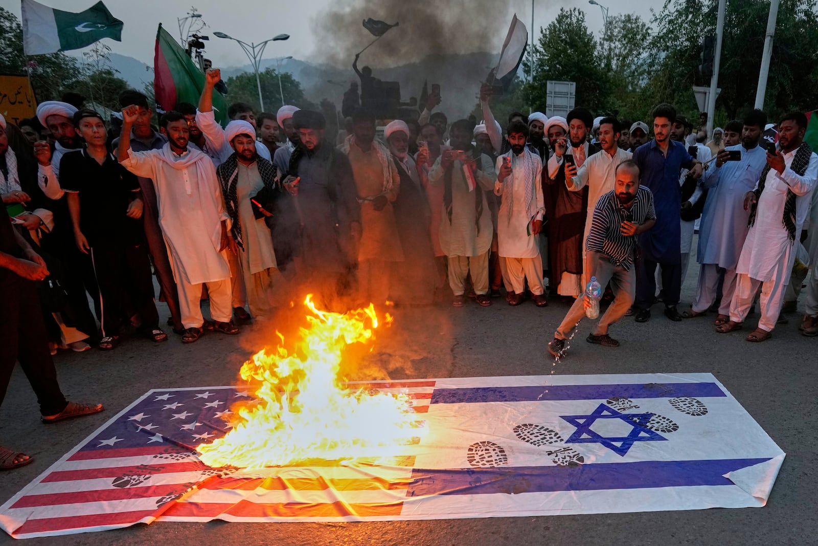 Shiite Muslims burn representations of U.S. and Israeli flags during a rally to condemn Israeli strikes on Iran, in Islamabad, Pakistan, Tuesday, June 17, 2025. (AP Photo/Anjum Naveed)