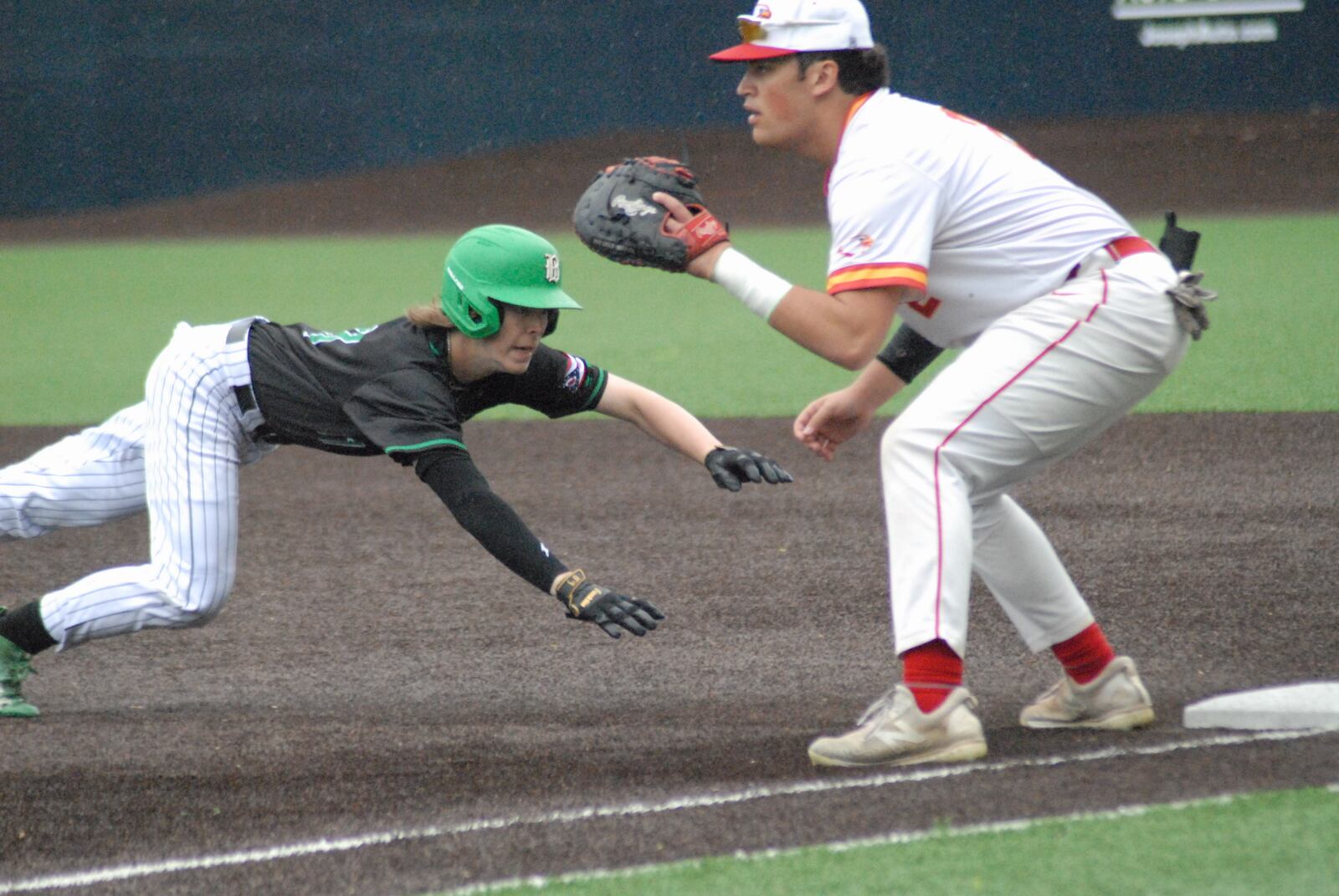 Badin sophomore Chase Luebbe dives back safely as Fenwick senior Matt Hensley tries to apply the tag during their game on Friday at Xavier University. Chris Vogt/CONTRIBUTED