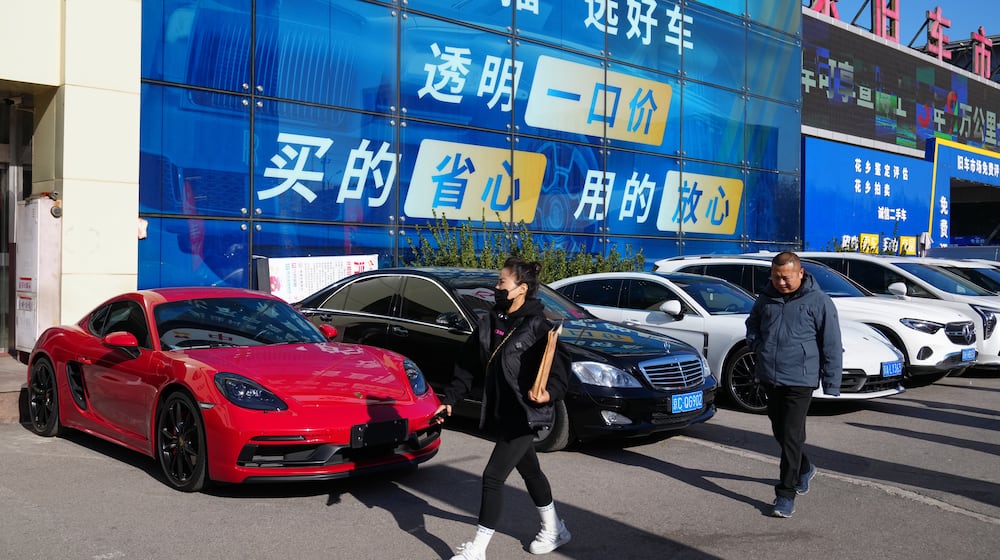 People walk past a second hand market for luxury cars in Beijing, Tuesday, Nov. 25, 2025. (AP Photo/Andy Wong)