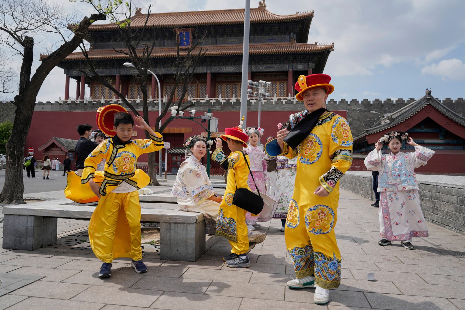 Tourists dressed as emperors react to strong winds outside the Forbidden City in Beijing, China, Saturday, April 12, 2025. (AP Photo/Ng Han Guan)