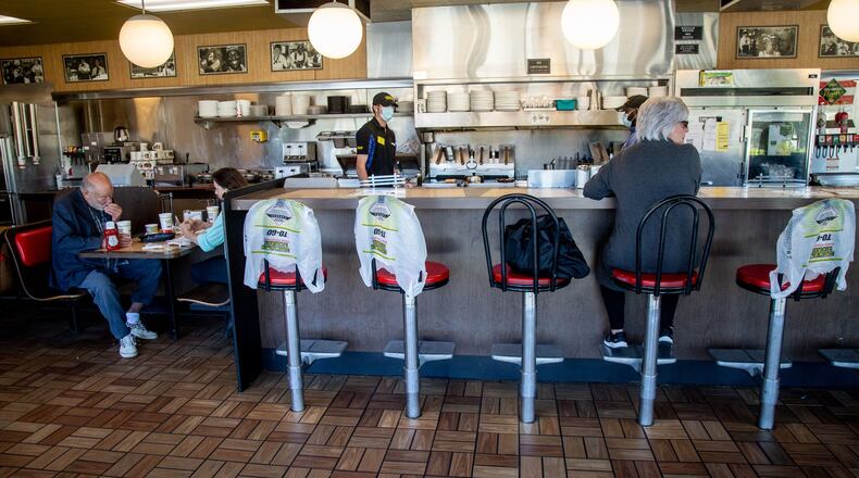 Kim Kaseta (L) waits for her pattie melt while sitting at the counter at the Waffle House in Brookhaven on Monday, when Georgia restaurants were allowed to have customers dine in again. The bags covering the chairs marked where customers weren’t allowed to sit in order to keep some social distancing. STEVE SCHAEFER / SPECIAL TO THE AJC