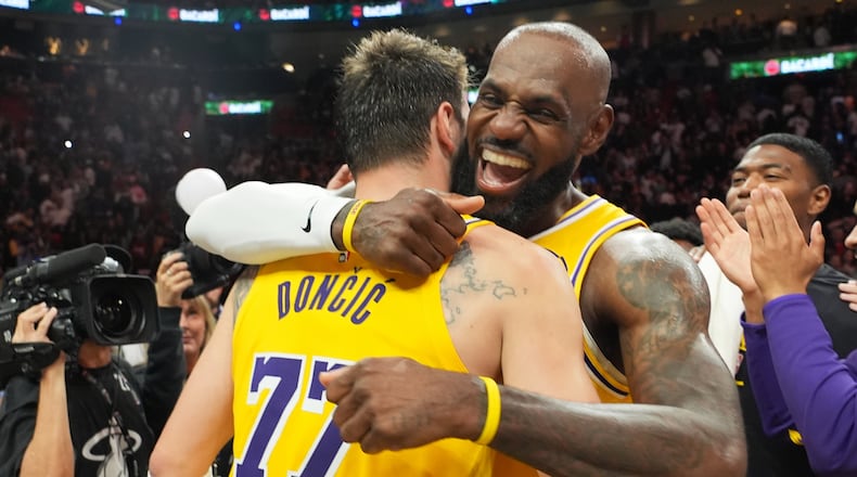 Los Angeles Lakers guard Luka Doncic (77) and forward LeBron James, right, embrace after defeating the Miami Heat in an NBA basketball game, Thursday, March 19, 2026, in Miami. (AP Photo/Lynne Sladky)