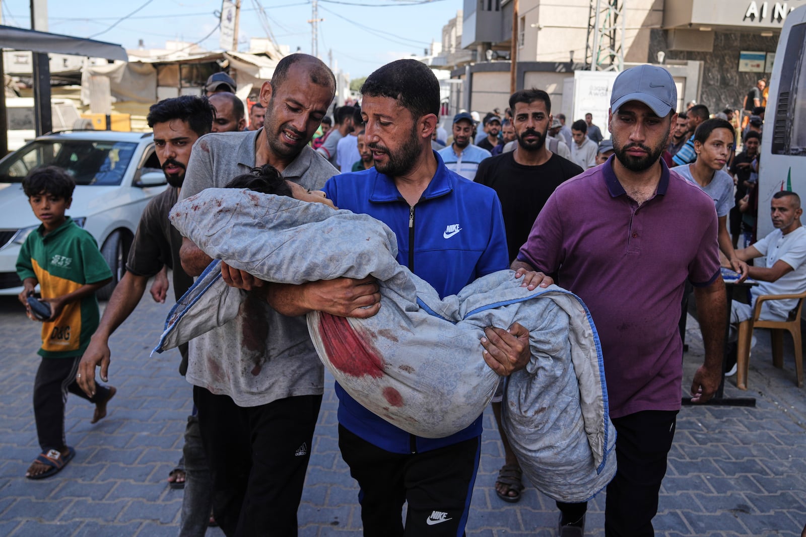 Relatives carry the body of 13-year-old Seraje Ebrahim, killed in an Israeli strike on a drinking water distribution point, for burial outside Al-Awda Hospital in Nuseirat, central Gaza Strip, Sunday, July 13, 2025. (AP Photo/Abdel Kareem Hana)