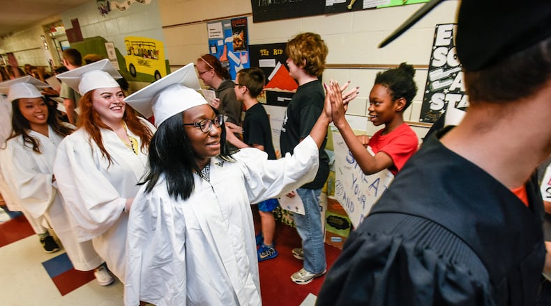 Lakota East senior Abena Acheampong gives a high five to Hopewell elementary sixth-grader Tafara Gwangwava as the soon-to-be graduating seniors marched through the hallway of Hopewell Elementary to the applause and cheers of the elementary students Monday, May 15. NICK GRAHAM/STAFF
