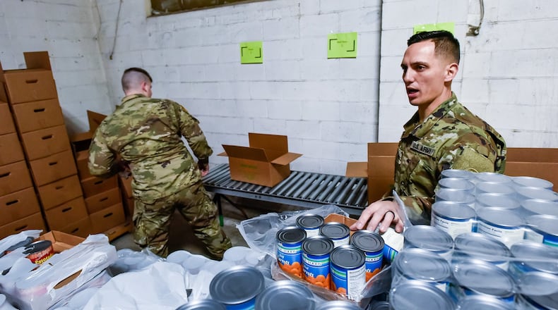 Spc. Seth Bentz, left, and Cpl. Michael Galbreath, members of the Ohio Army National Guard, pack boxes of food at Shared Harvest Food Bank Monday, March 23, 2020 in Fairfield. The Ohio Army National Guard was activated and helped pack food to be distributed to those in need throughout the area. NICK GRAHAM/STAFF
