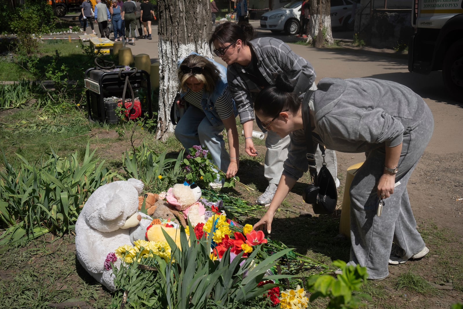 People lay flowers and toys on the site of Russia's deadly missile attack that hit residential houses Thursday killing 12 civilians and injuring 87 in Kyiv, Ukraine, Friday, April 25, 2025. (AP Photo/Efrem Lukatsky)
